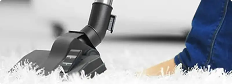 Close-up of a professional vacuuming a white carpet in Kansas City.