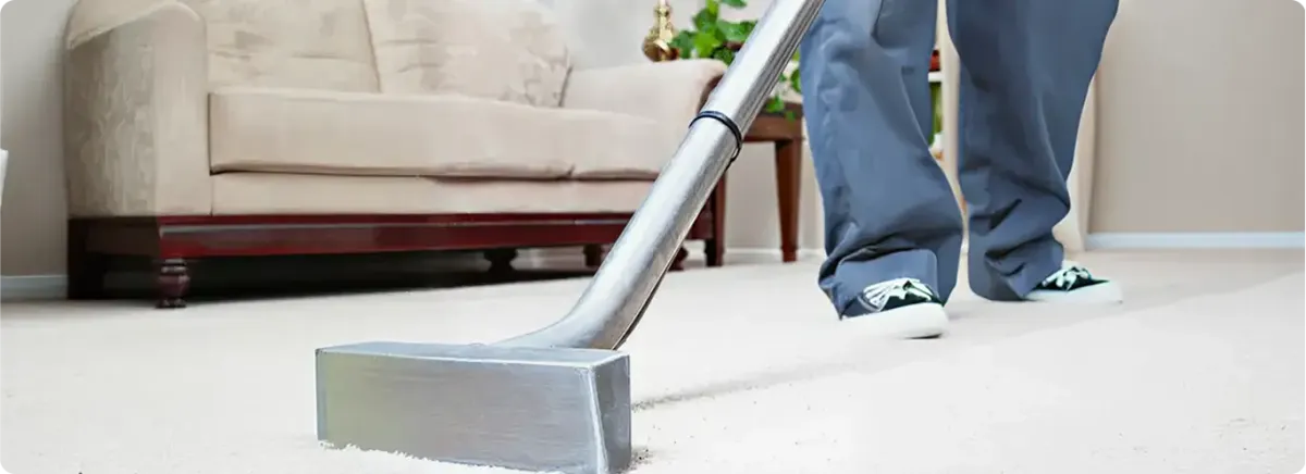 Carpet cleaning technician using a hot-water extraction wand on a light-colored carpet in a living room, Kansas City, KS.