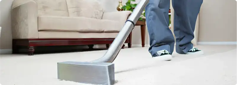 Carpet cleaning technician using a hot-water extraction wand on a light-colored carpet in a living room, Kansas City, KS.